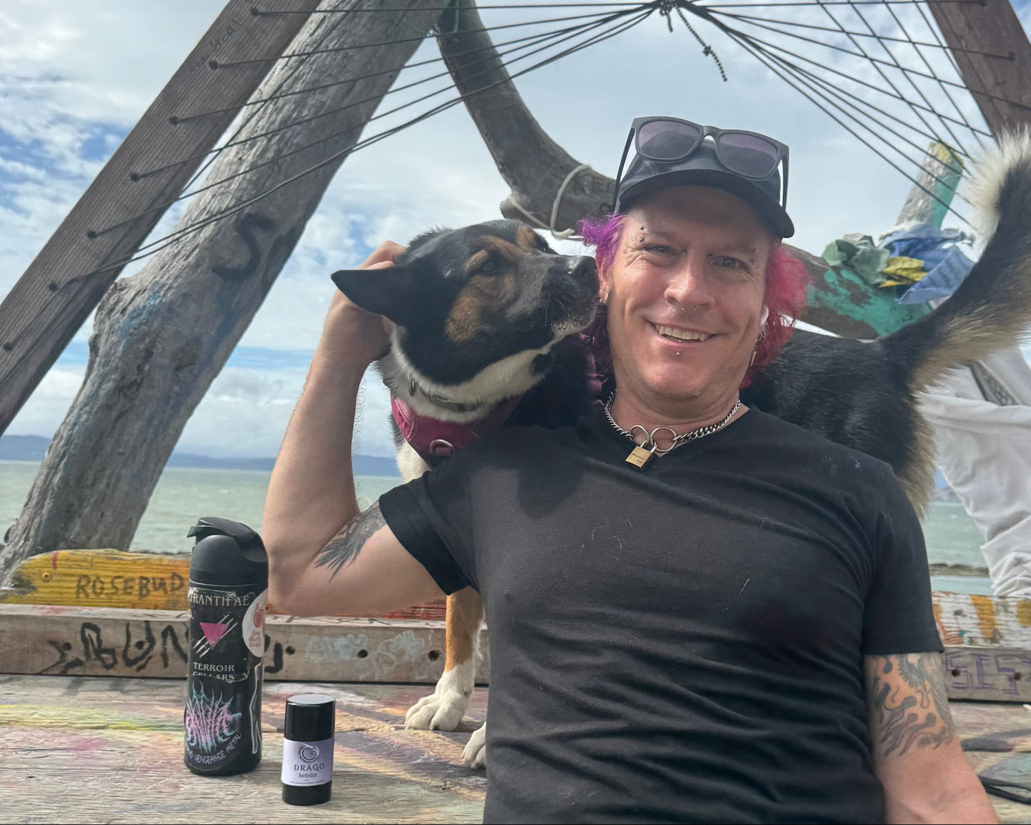genderqueer person holding dog with deodorant at the ocean